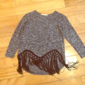 Long-sleeved shirt with fringes at the bottom.